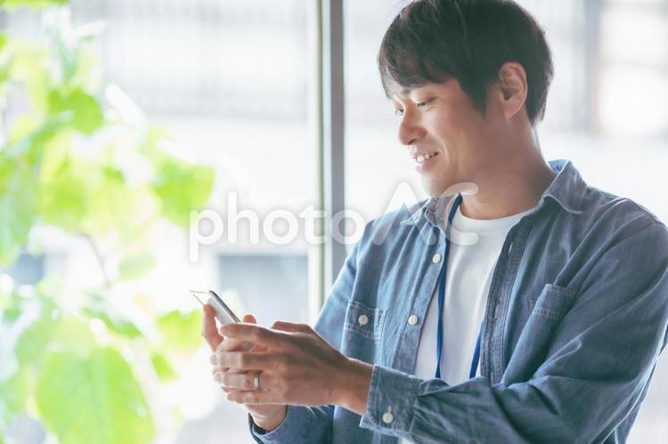 服装自由な会社でスマホを使う会社員 スマホ,検索,スマートフォンの写真素材