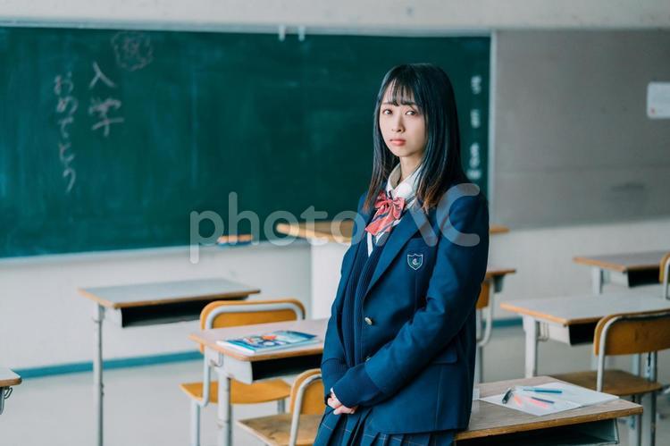 教室の机に腰掛ける女子高生 女子高校生,高校生,学生の写真素材
