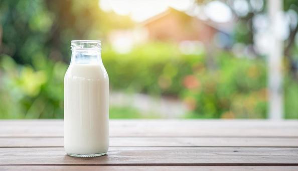 蓋の外された牛乳瓶と自然の背景 蓋の外された牛乳瓶と自然の背景の写真