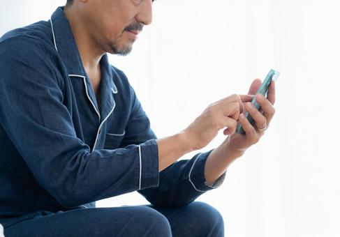 寝室でスマホを見るミドルの男性 寝室でスマホを見るミドルの男性 男性,スマホ,ミドルの写真素材