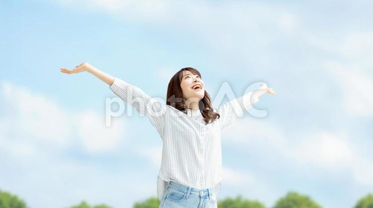 青空に両手を広げる笑顔の女性 女性,笑顔,春の写真素材