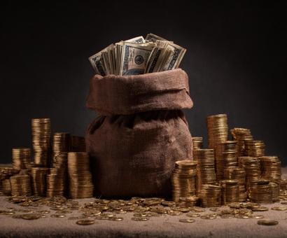 財産を象徴する、重厚な麻袋と金貨の写真