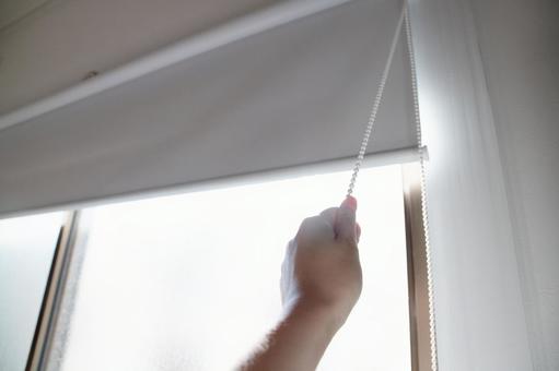 ロールスクリーンの紐を引っ張る手 ロールスクリーンの紐を引っ張る手 ロールスクリーン,ブラインダー,ロールカーテンの写真素材