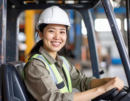 笑顔でフォークリフトを操作する女性作業員 笑顔でフォークリフトを操作する女性作業員の写真