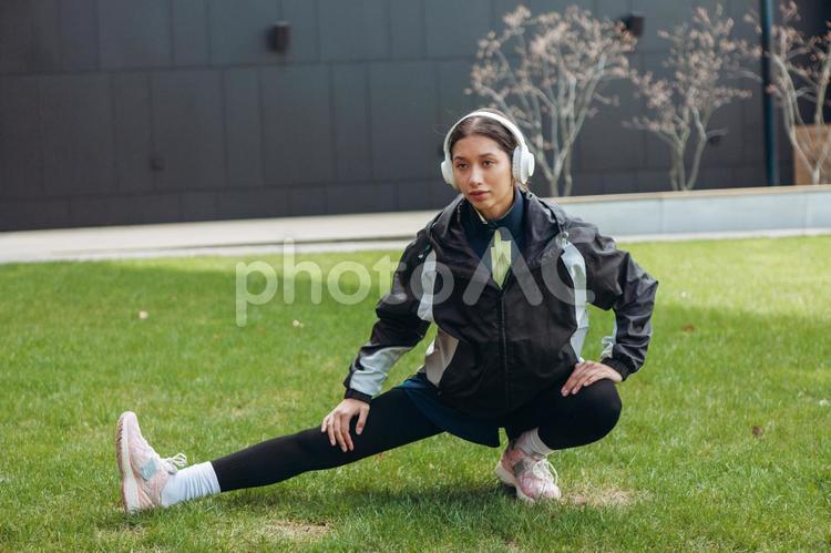 芝生でしゃがんで足を伸ばす女性 女性,ヘッドフォン,足を伸ばすの写真素材
