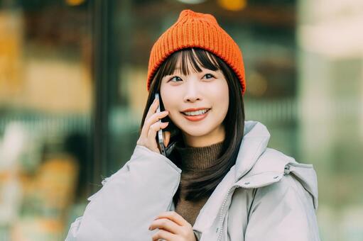 冬の街角でスマホを使う笑顔の女性 冬,女性,街の写真素材
