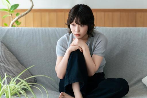 リビングのソファに座って考える女性 女性,考える,困るの写真素材