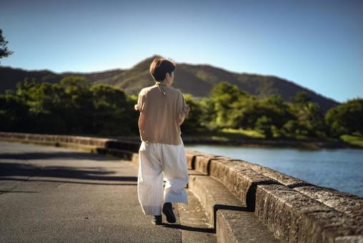 <Material> A woman walking along the sea at dawn on a trip, JPG