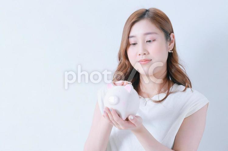 ブタの貯金箱を撫でる若い女性 女性,貯金箱,節約の写真素材