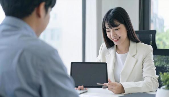 タブレットを使って説明する女性営業マン タブレットを使って説明する女性営業マンの写真