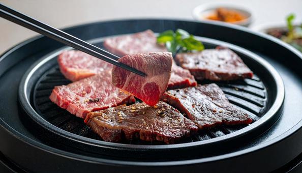 焼肉を鉄板で焼いて鉄箸ですくう 焼肉を鉄板で焼いて鉄箸ですくうの写真