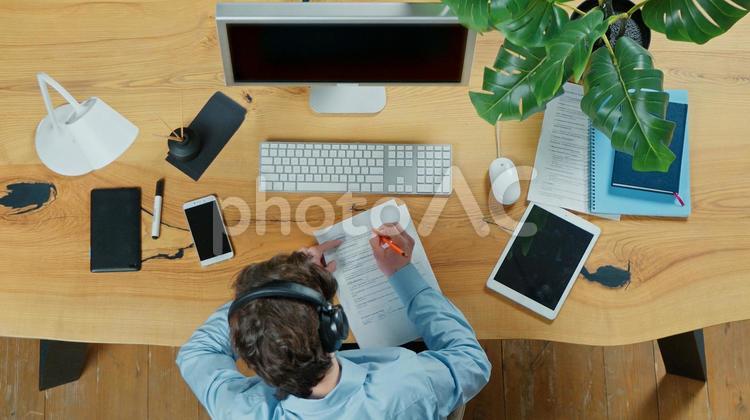 上から見た書類に記入している人 男性,ヘッドホン,聞くの写真素材