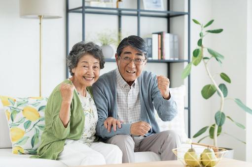 リビングでくつろぐシニアの夫婦 シニア,ガッツポーズ,夫婦の写真素材