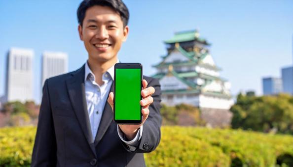 携帯画面を見せて笑うビジネスマン 携帯画面を見せて笑うビジネスマンの写真