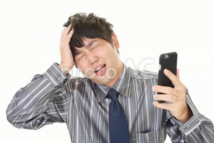 スマホを持って困った表情の男性 男性,スマホ,ビジネスの写真素材