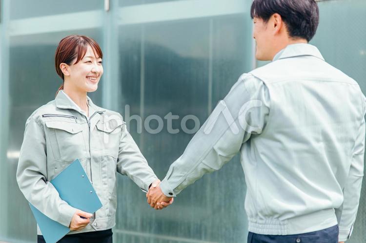 握手する作業着姿の男女（契約） 握手,契約,作業服の写真素材