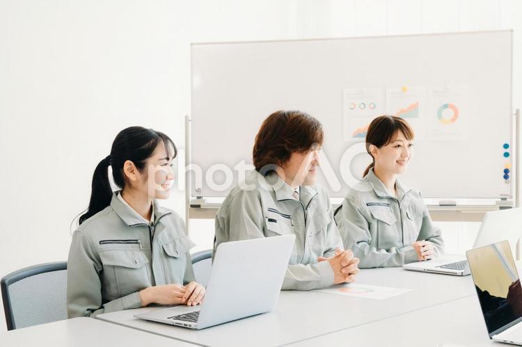 会議をする作業着をきた会社員（提案・3人） 作業服,会議,ビジネスの写真素材