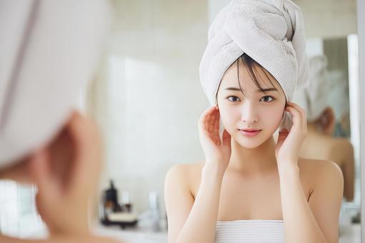 入浴後にタオルを頭に巻き鏡を見つめる女性 入浴後にタオルを頭に巻き鏡を見つめる女性の写真