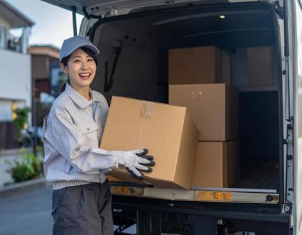 トラックから荷物を出す宅配女性ドライバーの写真