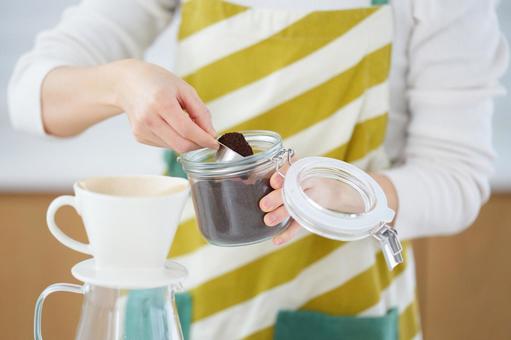 コーヒーの粉を計量スプーンに入れ持つ人の手元 コーヒーの粉を計量スプーンに入れ持つ人の手元の写真