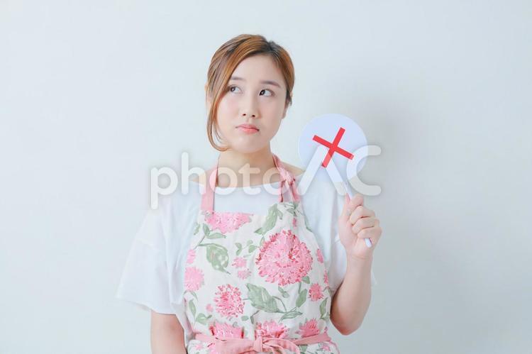 左手で×札を持つ不機嫌そうな女性 女性,日本人,×の写真素材