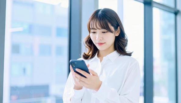 スマホを確認するビジネス女性の写真
