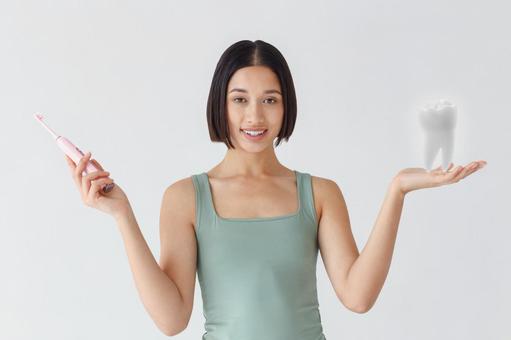 電動歯ブラシを持って片手に歯の模型を持っている女性 電動歯ブラシを持って片手に歯の模型を持っている女性 111,女性,歯ブラシの写真素材