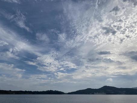 空のキャンパスに描かれた雲と静寂の湖の写真