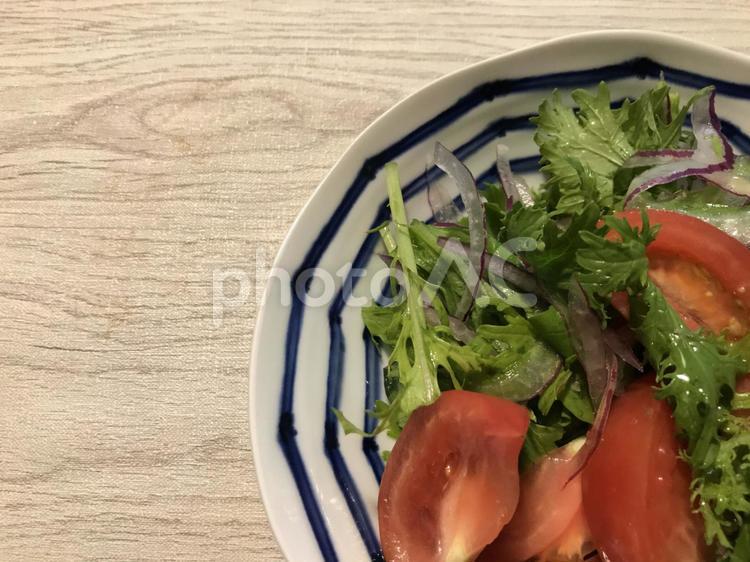木目のテーブルに置かれたトマトとルッコラと玉ねぎとわさび菜のサラダ サラダ,トマト,ルッコラの写真素材