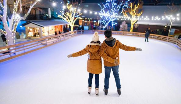 アイススケートリンクで滑るカップル アイススケートリンクで滑るカップルの写真