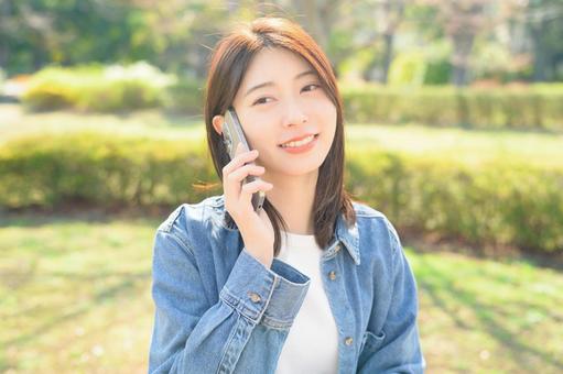 公園で電話をする女性 公園で電話をする女性の写真