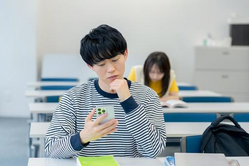スマホを見ながら悩む大学生 スマホ,大学生,男性の写真素材