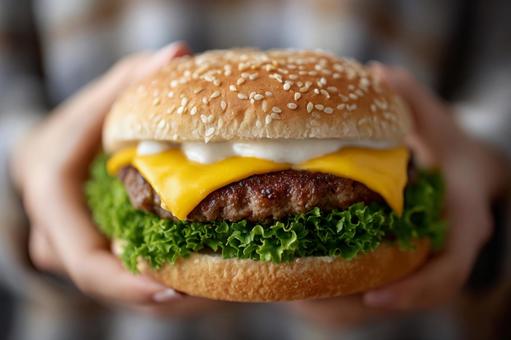 両手で持った大きなチーズバーガー 両手で持った大きなチーズバーガーの写真