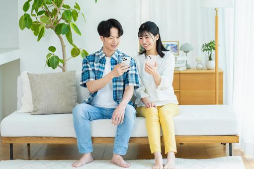 リビングでスマホを見るカップル リビングでスマホを見るカップル スマホ,笑顔,カップルの写真素材