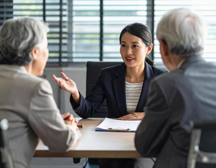 顧客と話をするスーツ姿の女性 顧客と話をするスーツ姿の女性の写真
