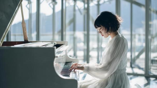 白いドレスを着てピアノを弾く女性 白いドレスを着てピアノを弾く女性の写真