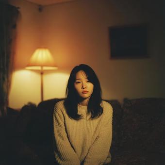 温かい照明の下で静かに佇む女性 温かい照明の下で静かに佇む女性の写真