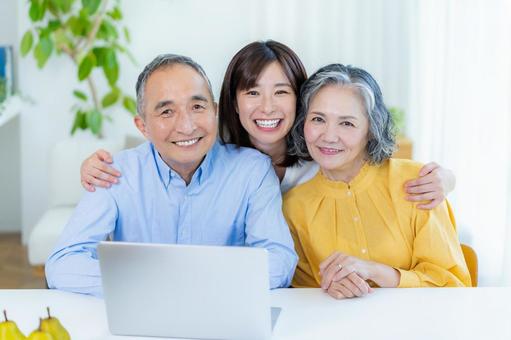 リビングでパソコンを見る親子 リビングでパソコンを見る親子 シニア,夫婦,子供の写真素材