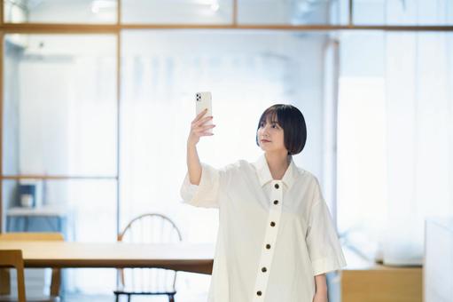 A woman holding a smartphone indoors, đàn bà, điện thoại thông minh, điện thoại thông minh, JPG