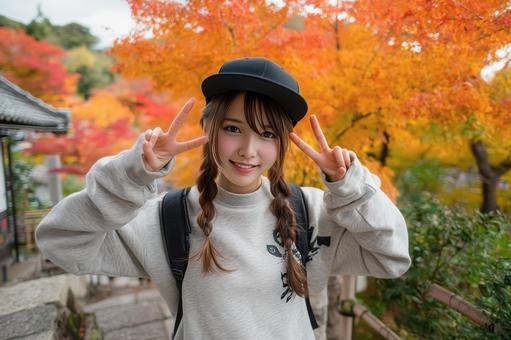 紅葉を楽しむピースサインをする女性の写真