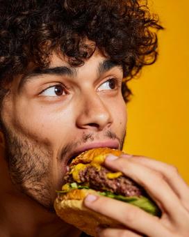 美味しそうにハンバーガーを食べる若者 美味しそうにハンバーガーを食べる若者の写真