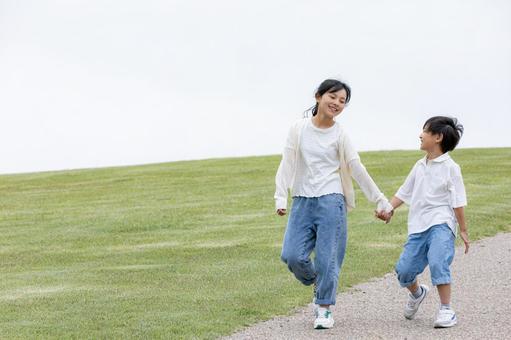 丘の上を笑顔で歩く子ども 丘の上を笑顔で歩く子どもの写真