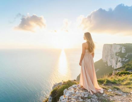 夕日を眺める女性　海と断崖の写真