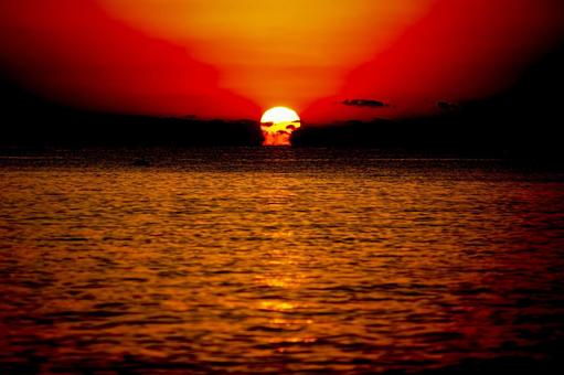 ＜素材＞夕方の海に沈む太陽の写真