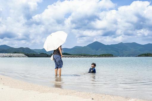 <素材>夏の海で子供が遊ぶ姿を見守る母 <素材>夏の海で子供が遊ぶ姿を見守る母 子供,男性,人物の写真素材