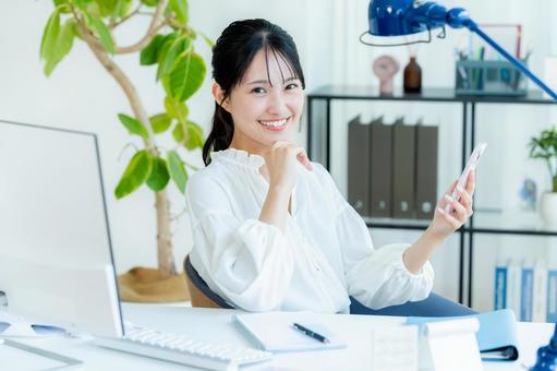 オフィスでスマホを持つビジネスウーマン スマホ,笑顔,ビジネスウーマンの写真素材