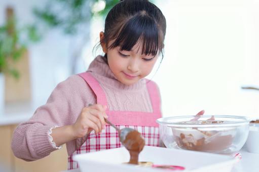 お菓子作りを楽しむピンクのエプロン姿の少女 女の子,チョコレート,スプーンの写真素材
