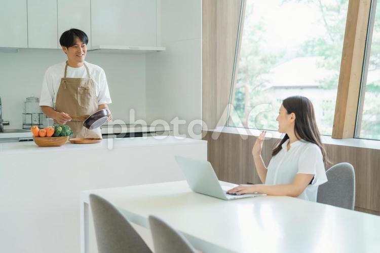 テレワークする女性と料理を作る男性 テレワーク,家事,夫婦の写真素材