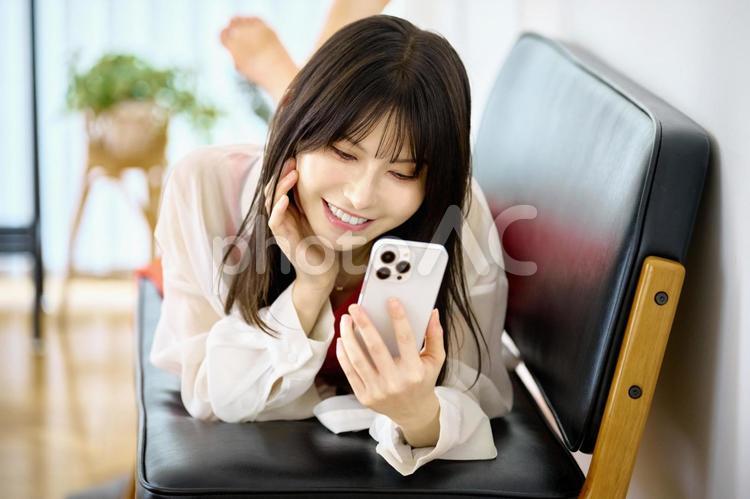 スマホを見る女性　ソファ　寝転がる スマホ,女性,ソファの写真素材