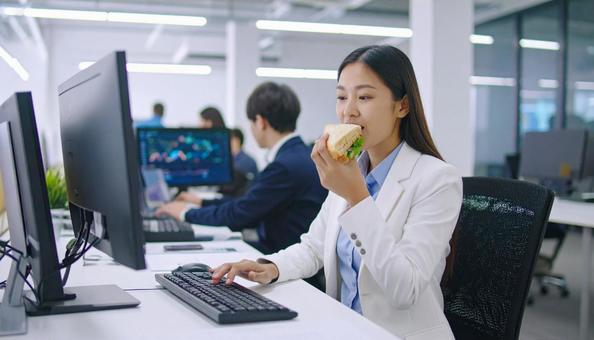 昼食を食べながら仕事するビジネスウーマン 昼食を食べながら仕事するビジネスウーマンの写真